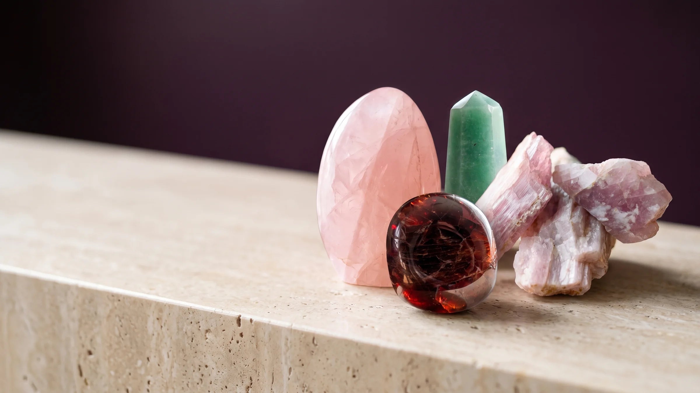 Rose quartz, garnet, green aventurine and kunzite grouped in soft light.