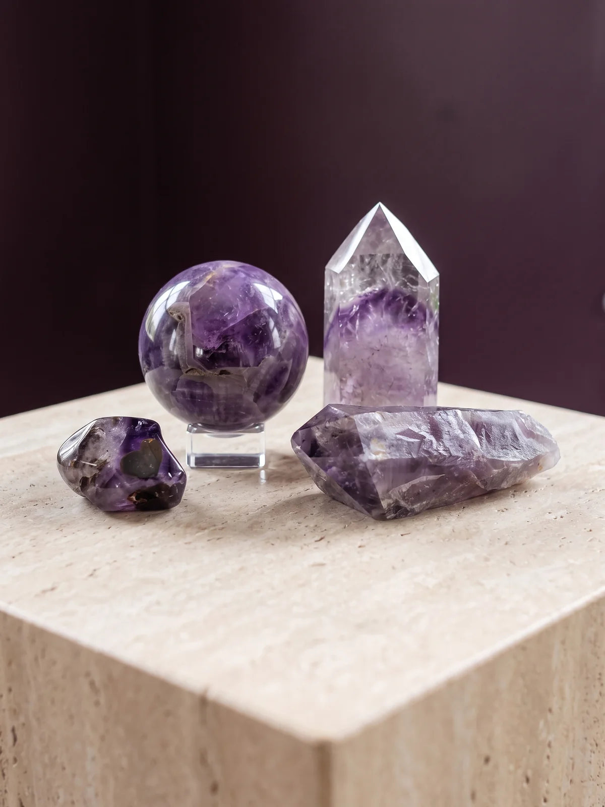 Amethyst in four forms — raw point, sphere, tower and tumbled stone.