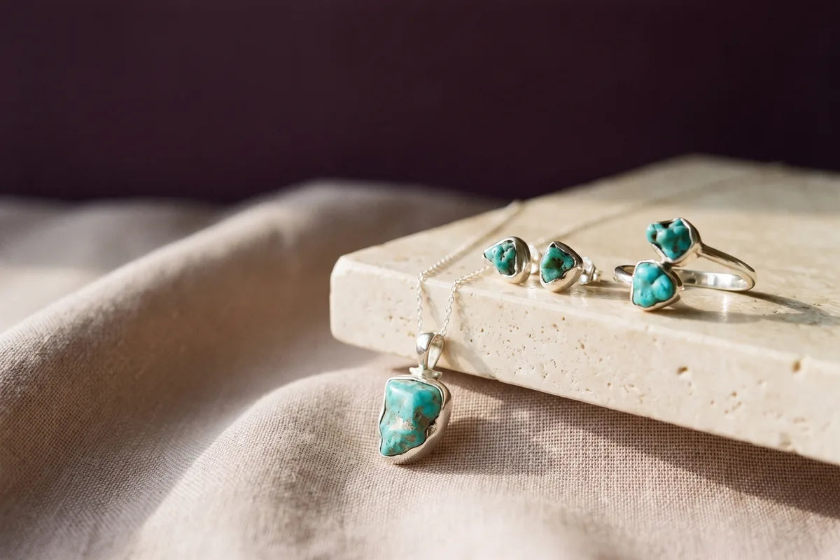A turquoise jewelry gift set — earrings, pendant, and ring — in soft studio light.